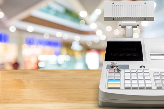 Kasa fiskalna z kluczykiem na ladzie w galerii handlowej.