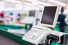 Stanowisko kasowe z monitorem i czytnikiem kodów w supermarkecie.